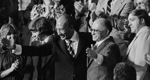 Der ägyptische Präsident Anwar as-Sadat und Israels Premierminister Menachem Begin empfangen Applaus und grüßen.