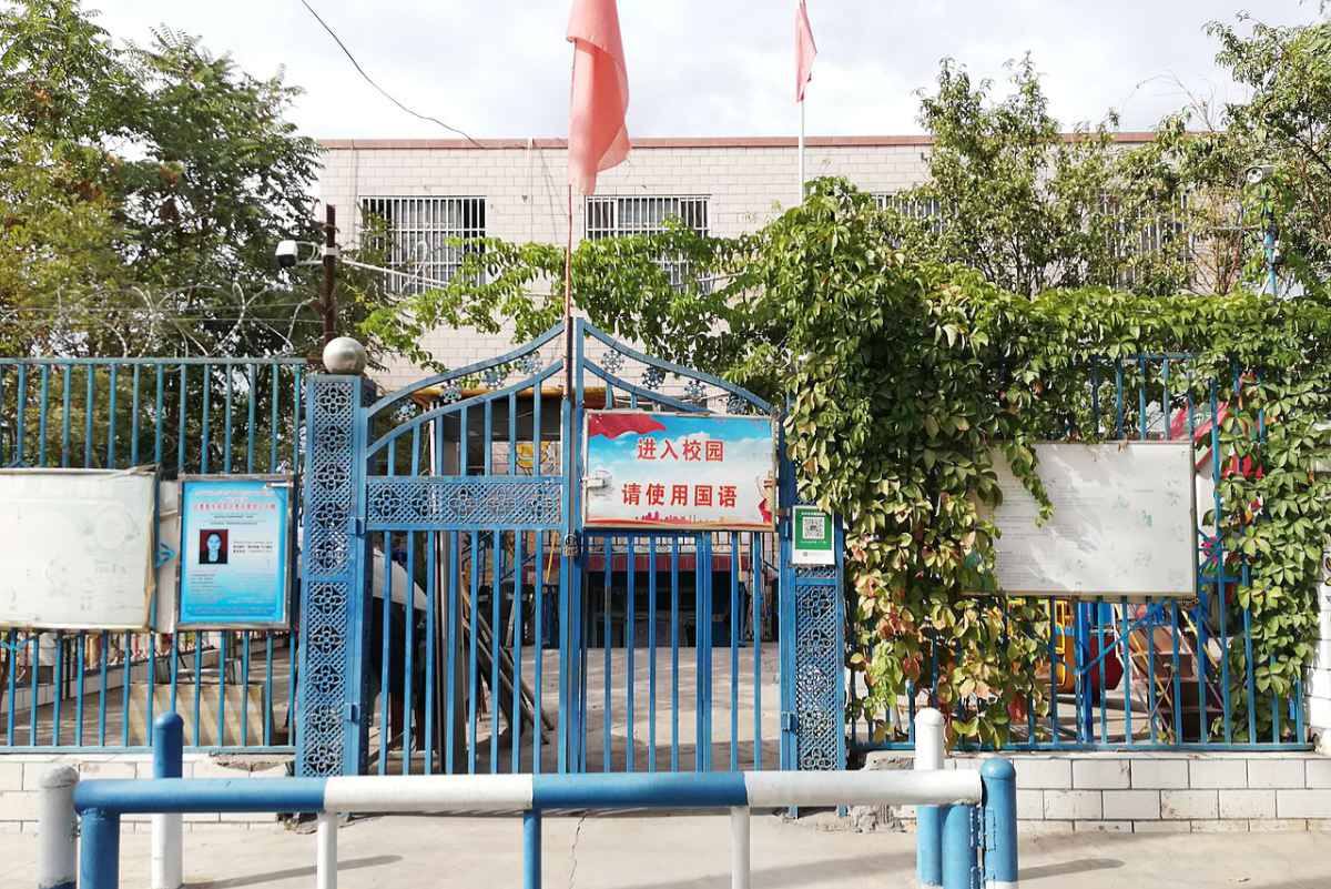 Ein Schulgebäude in der Stadt Turpan in Xinjiang. Auf dem am Tor angebrachten Schild steht: „Eingang zum Schulgelände. Bitte sprechen Sie chinesisch“.