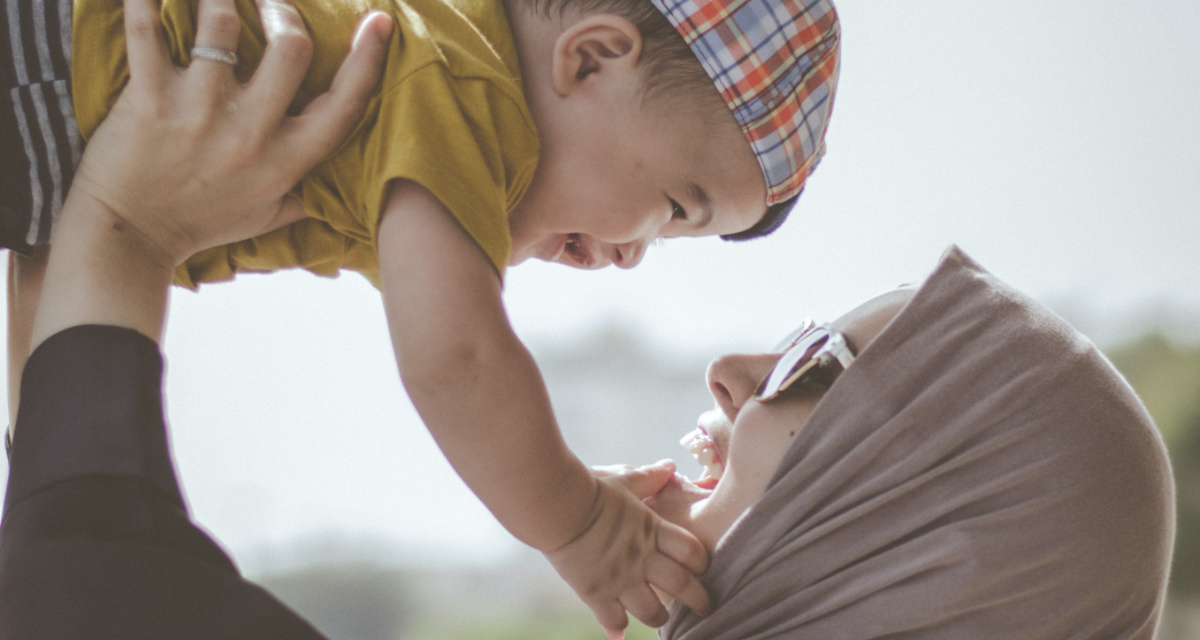 Lachende Frau hebt lachendes Baby in die Luft. Foto: unsplash | M.T ElGassier