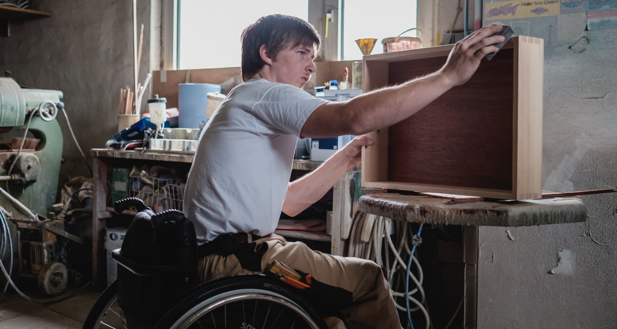 Junger Mann im Rollstuhl, der eine Ausbildung zum Tischler absolviert. Foto: gesellschaftsbilder | Andi Weiland