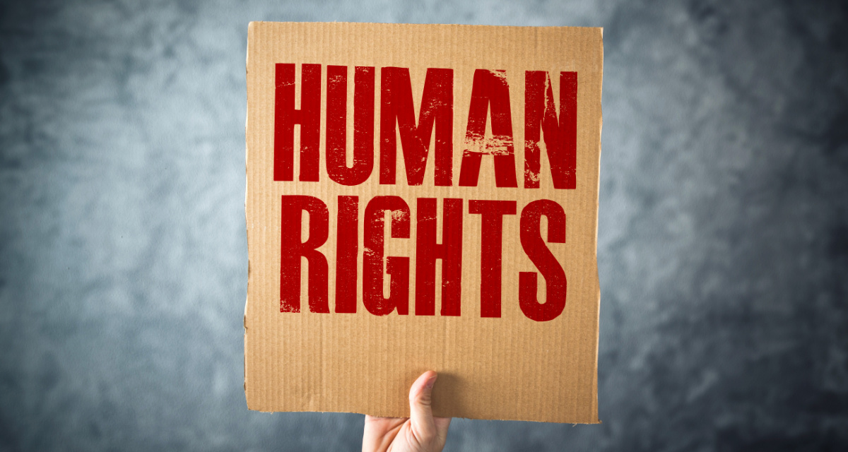 Hand hält Pappschild mit Aufschrift „Human Rights“.