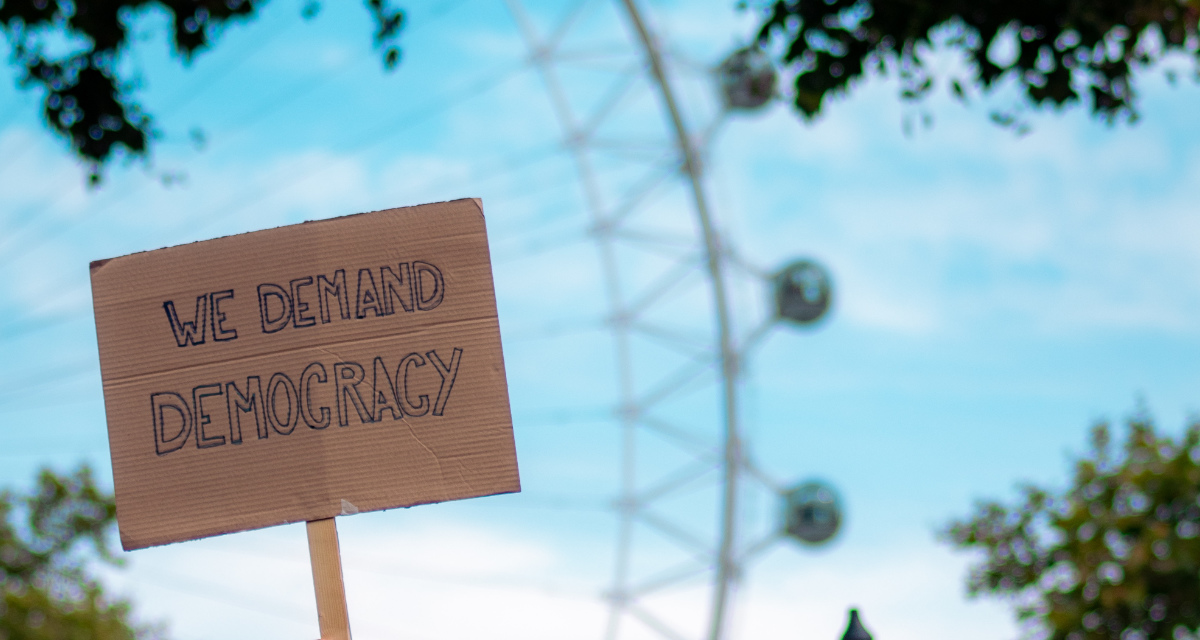 Auf einer Demonstration wird nach Demokratie verlangt. Foto: unsplash/Fred Moon.