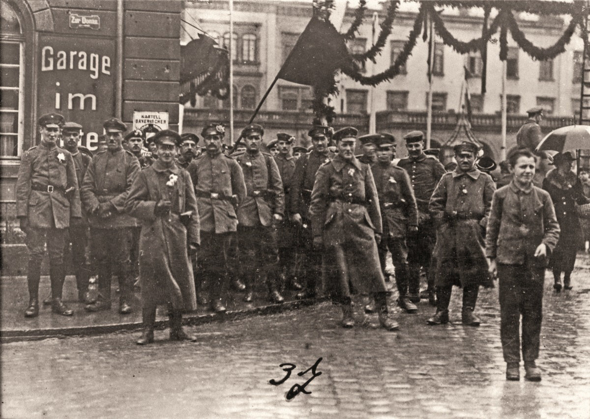 Das Foto zeigt Ulmer Soldatenräte mit (vermutlich) roter Fahne auf dem Ulmer Bahnhofsplatz im November 1918. 